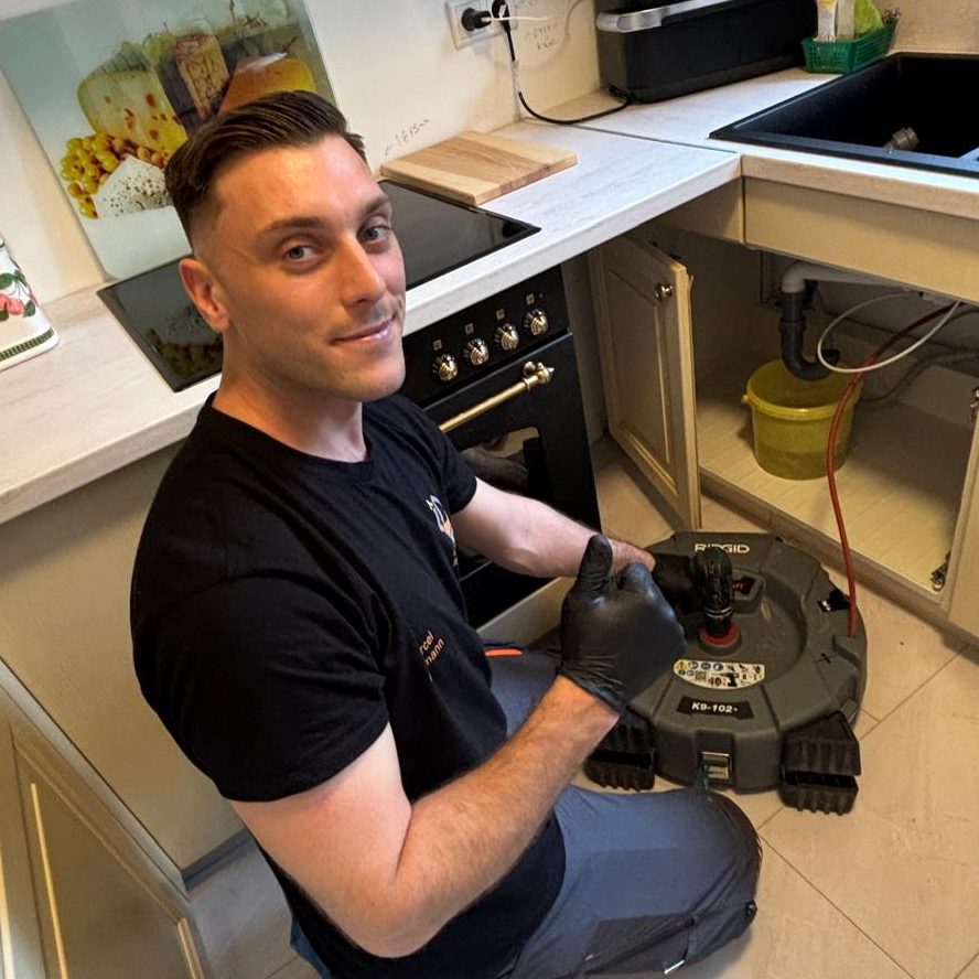 Ein Rohrreiniger ist beim Kunden Der Rohrreiniger geht seiner arbeit nach und löst ein Kundenproblem in der Küchen am Küchenabfluss.